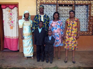 Bannyuy stands in front of his house with his sons Evance and Justine, his sister, neighbor and housekeeper.